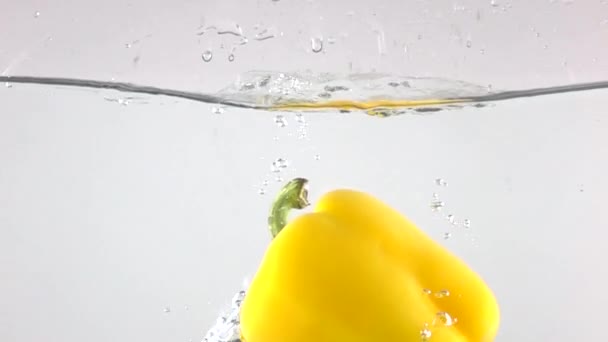 Super slow motion shot of yellow bell pepper falling down in water — Stock Video