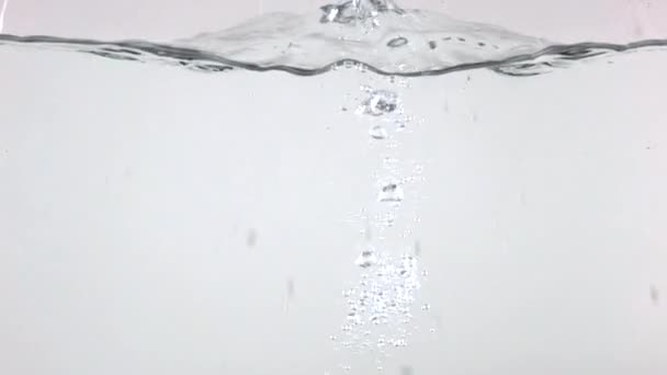 Супер замедленная съемка грязного картофеля, падающего в воду на светлом фоне — стоковое видео