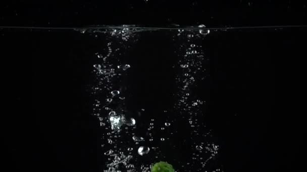 Два зеленых огурца, падающих в воду, видео сверхмедленного движения — стоковое видео