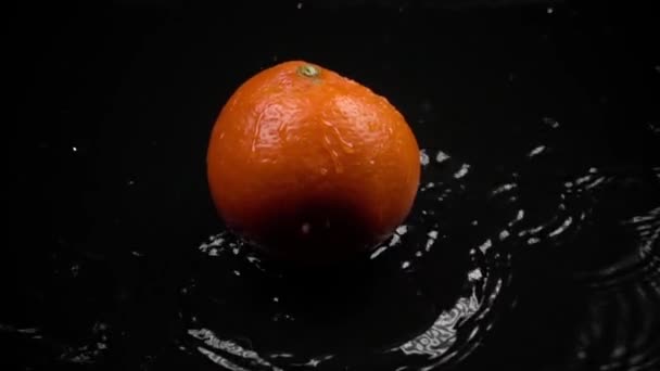Супер замедленный снимок оранжевого удара о темную поверхность — стоковое видео