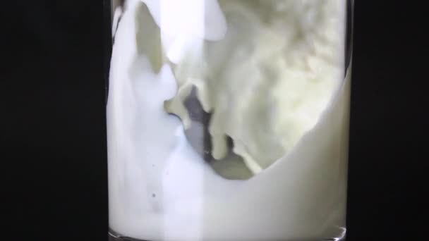 Primer plano de toma en cámara lenta extrema de leche que se vierte en un vaso — Vídeo de stock