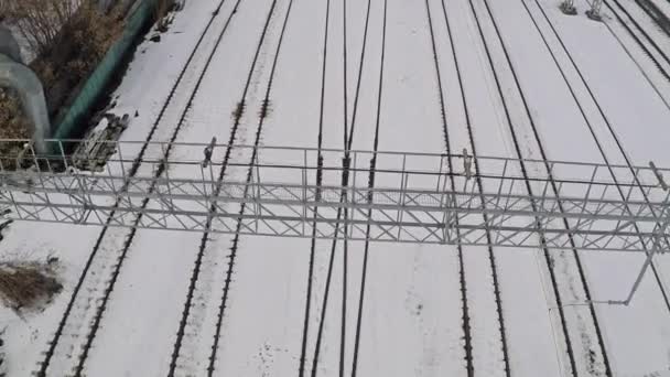 Vários trilhos ferroviários eletrificados e interruptores na neve. Vista aérea — Vídeo de Stock