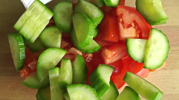 Poner los ingredientes de la ensalada griega en un tazón de vidrio, ver desde arriba — Vídeos de Stock