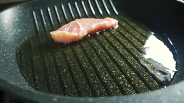 Woman placing two pieces of turkey fillet on hot grill pan with oil — Stock Video