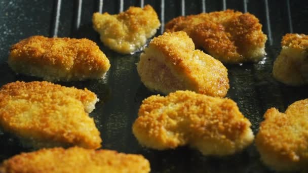 Golden breaded meat pieces sizzling on a grill pan — Stock Video