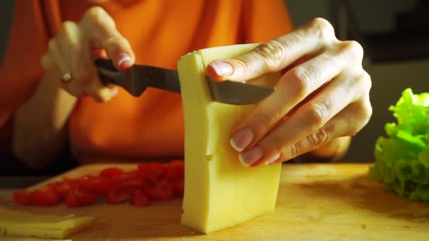 Giovane donna che taglia formaggio per panino sul tagliere — Video Stock