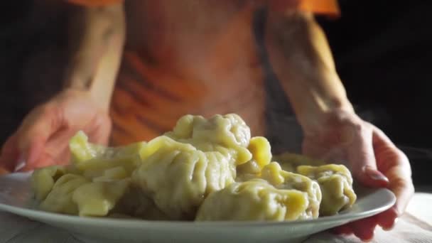 Mujer joven en naranja que sirve pelmeni recién hervido, cocina rusa — Vídeo de stock