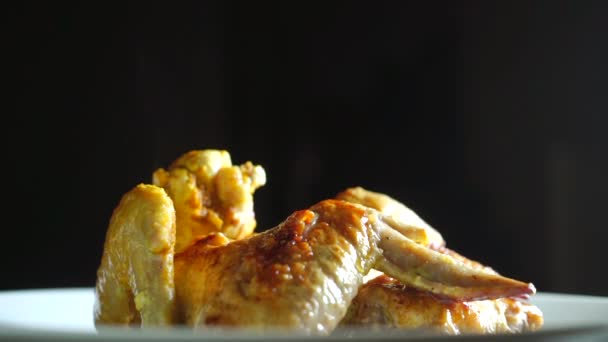 Stomen van gebakken kip vleugels op plaat tegen de donkere achtergrond, slow-motion video — Stockvideo