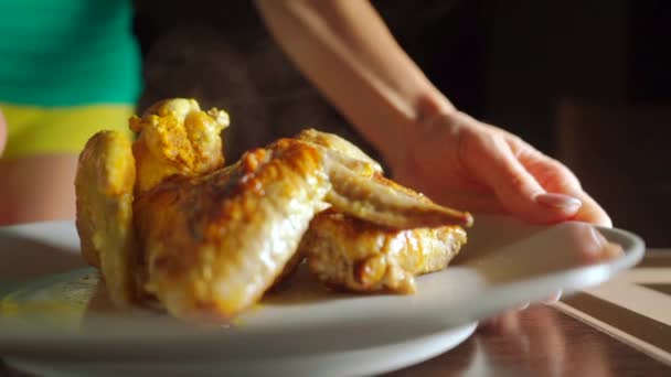 Девушка, подающая жареные куриные крылышки на тарелке, видео замедленного действия — стоковое видео
