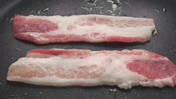 Close up video of two horizontal frying bacon slices — Stock Video