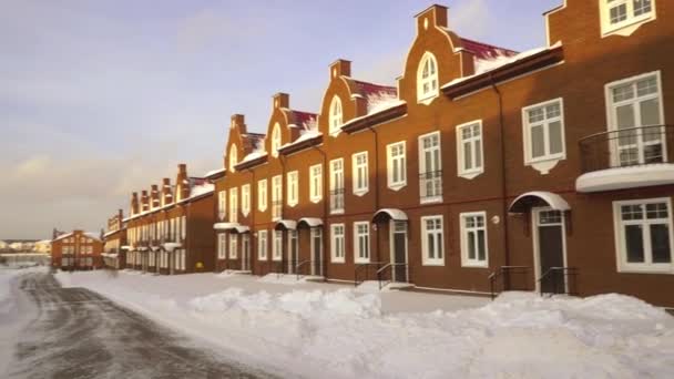 Panorámica estableciendo plano de casas adosadas de ladrillo rojo en día soleado nevado — Vídeos de Stock