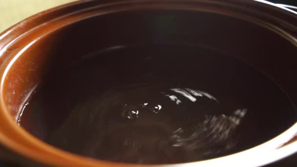 Zouten van warm water in bruine pot — Stockvideo