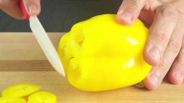 Mann schneidet gelben Paprika mit weißem Messer. Nahaufnahme — Stockvideo