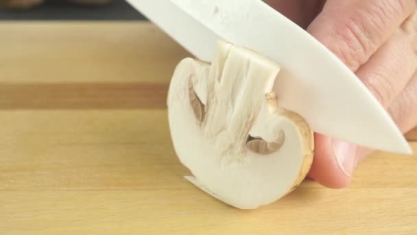 Нарезка полевых грибов на легкой деревянной доске — стоковое видео