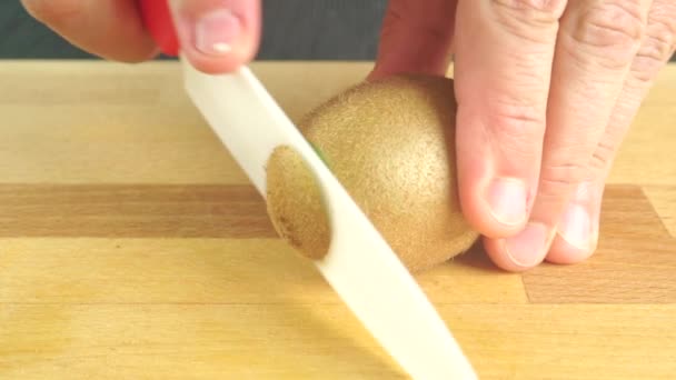 Разрезание киви белым керамическим ножом — стоковое видео