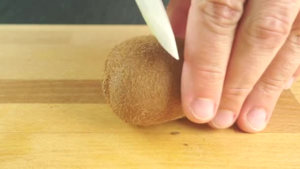 Man hands dividing kiwi with white knife — Stock Video
