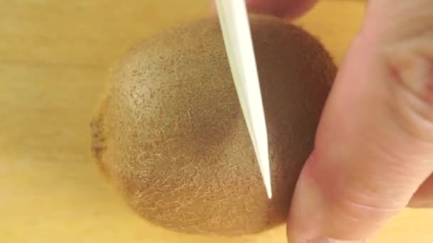 Seorang pria membagi buah kiwi dengan pisau putih — Stok Video