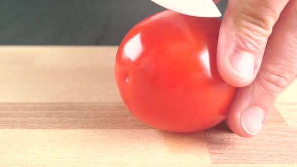 Muž řezání celý zralé červené rajče s bílými nůž. Zblízka střílel — Stock video