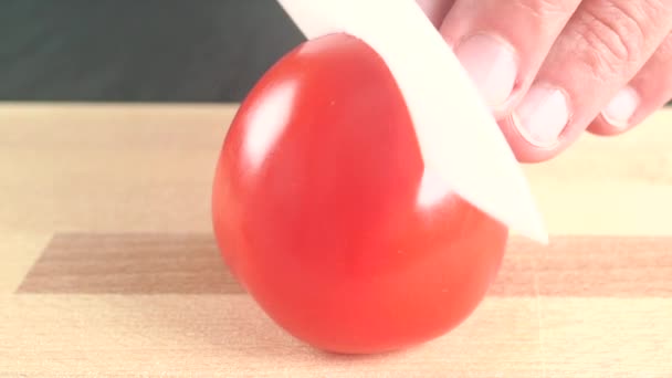 Hombre dividiendo tomate rojo maduro con cuchillo blanco. Primer plano. — Vídeos de Stock