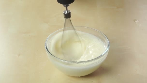 Preparing cream in a glass bowl with handheld blender — Stock Video