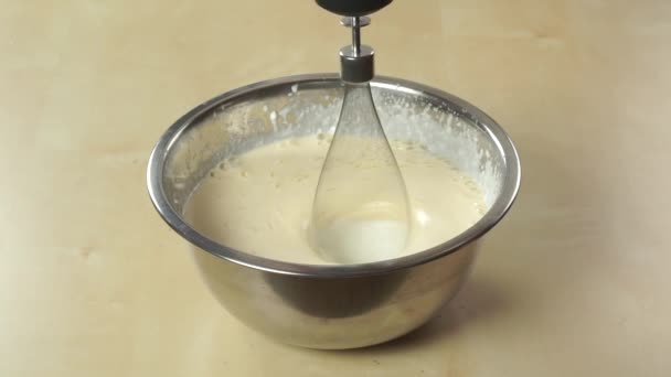 Подготовка крема в блестящей стальной чаше с ручным блендером — стоковое видео