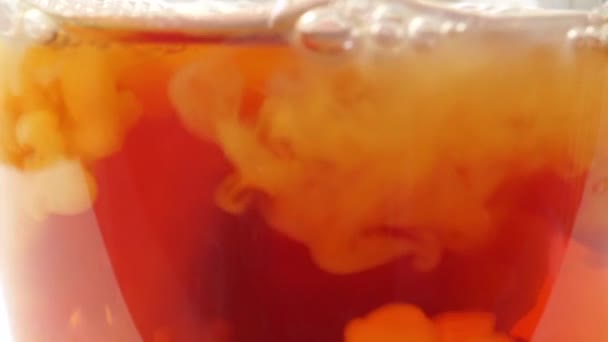 Adding milk to black tea in a glass mug, extreme close up — Stock Video