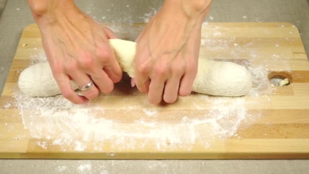 Las manos de mujer extendiendo la masa en una tabla de madera — Vídeos de Stock