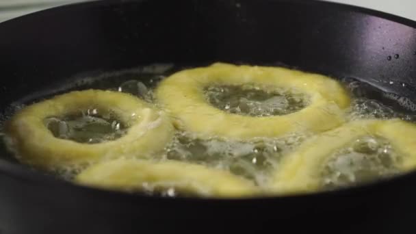 Vier donuts frituren in olie in een pan — Stockvideo