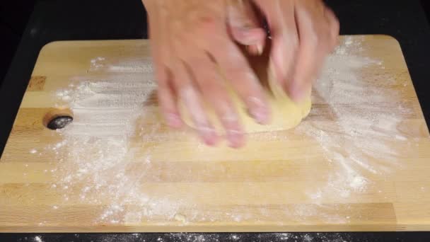Man hands kneadding dough on light wooden cutting board — Stock Video