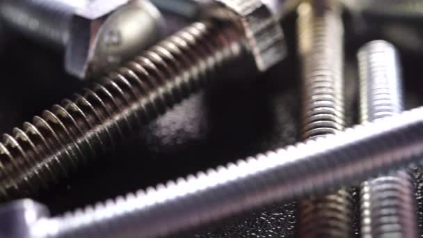 Dolly shot of various steel bolts on dark background — Stock Video