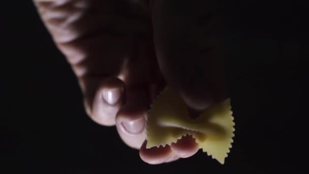 Man hand een stukje farfalle pasta neerzetten en draaien — Stockvideo