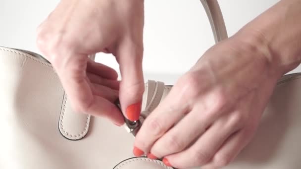 Girl with red nail polish opening and closing her beige leather bag — Stock Video
