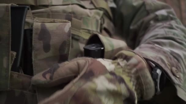 El soldado pone munición de rifle de asalto en los bolsillos de su chaleco de munición. Primer plano. — Vídeo de stock