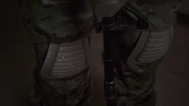Żołnierz noszący kamuflażu trzyma karabin szturmowy w półmroku. Panoramowanie pionowe — Wideo stockowe