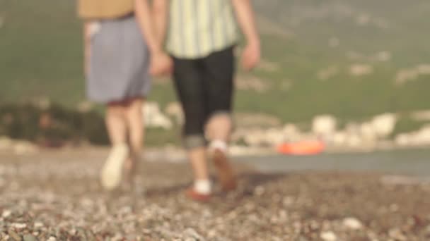 Loving couple walking along the coast holding hands and kissing blurred — Stock Video