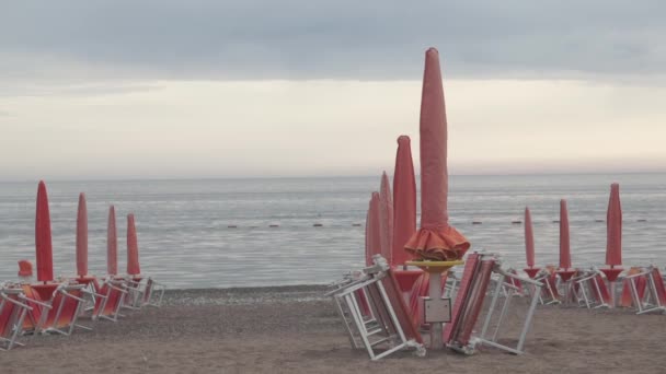 Sombrillas cerradas en la playa por la noche — Vídeo de stock