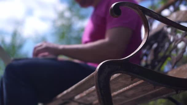 Man arbetar på en bänk med sin laptop och sedan gå bort — Stockvideo