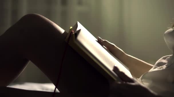 Αγνώριστος κορίτσι διαβάζοντας ένα βιβλίο στο κρεβάτι της το βράδυ — Αρχείο Βίντεο