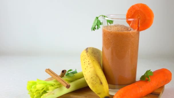 Orange smoothy in a glass. Banana, carrot, parsley and celery. 4K dolly video — Stock Video