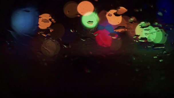 Abstract night street bokeh circles and rain drops on a wind screen — Stock Video