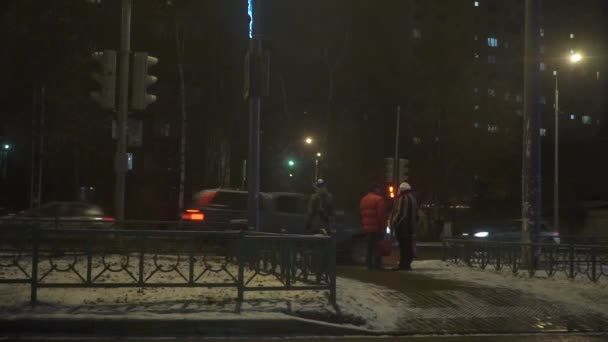 Menschen überqueren die vielbefahrene Straße mit einer Ampel. Video vom späten Abend — Stockvideo