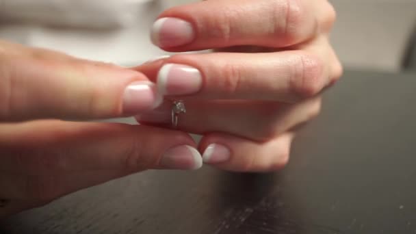 Молода жінка з красивим лаком для нігтів наносить діамантове кільце на її палець — стокове відео