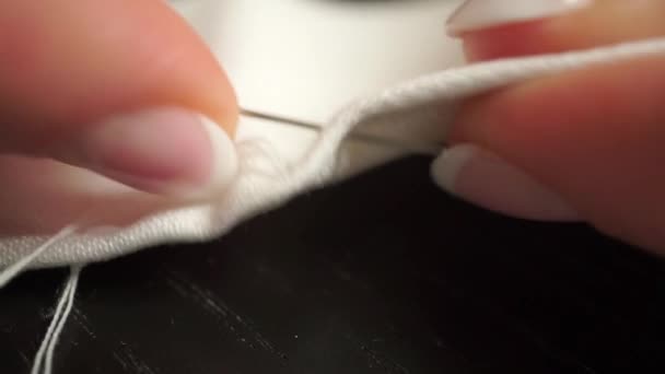 Vídeo macro de hermosas manos de mujer cosiendo un paño blanco con hilo blanco — Vídeo de stock