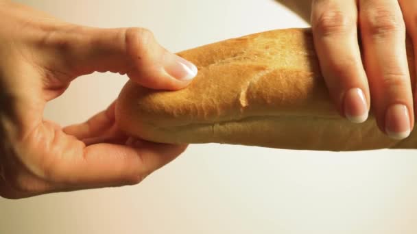 Chica manos con un esmalte de uñas romper un poco de pan de trigo francés fresco — Vídeos de Stock