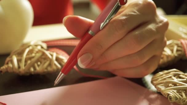 Hermosa chica con un vestido rojo que comienza a componer una carta romántica — Vídeos de Stock