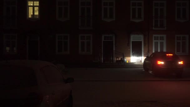 Stor bil enheter från ett rött tegel townhouse på natten — Stockvideo