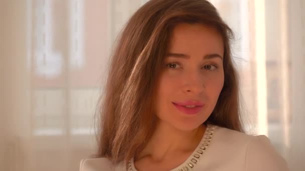 Schöne junge Frau mit roten Lippen und langen Haaren, die in die Kamera lächelt — Stockvideo