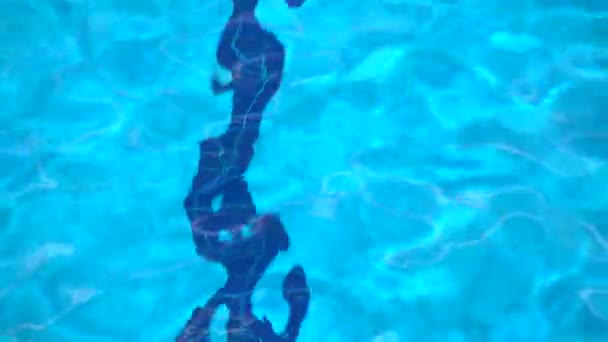 Azulejos azules en la parte inferior de la piscina. Ondulación del agua, vista desde arriba, 4K — Vídeo de stock