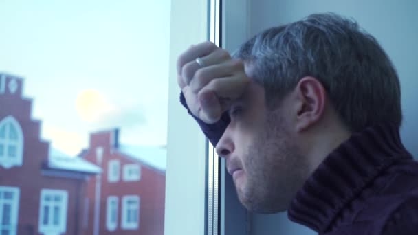 Verontrust jonge man met grijs haar op zoek door het raam — Stockvideo