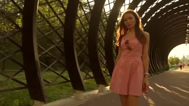 ピンクのドレスで美しいブルネットの少女は、アーチ型の通路がについて説明します。スローモーション ステディカム クリップ — ストック動画
